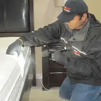Bed bug inspection technician checking a mattress and bed frame for signs of infestation in Hialeah, FL