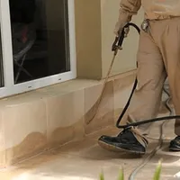 General pest control technician spraying exterior perimeter around a home in Hialeah, FL