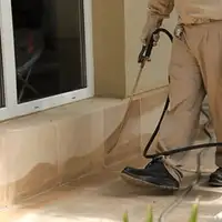 General pest control technician spraying exterior perimeter around a home in Hialeah, FL